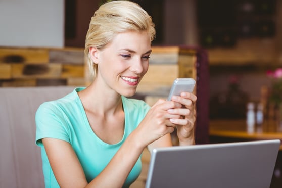 Pretty blonde woman using her smartphone at the cafe